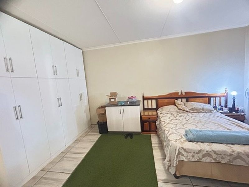 A bedroom featuring extensive white built-in cupboards, tiled flooring, and neutral wall finishes.