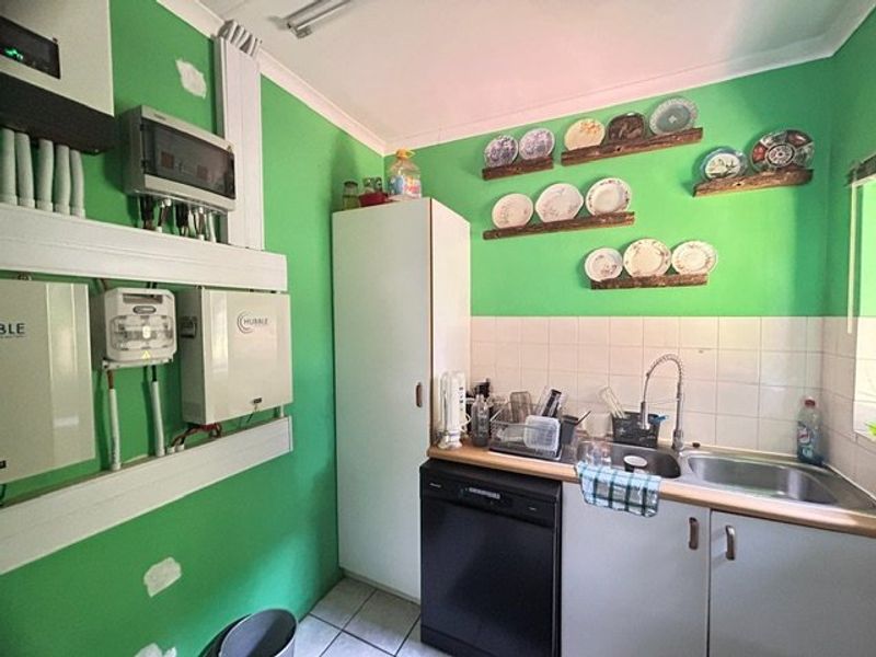 Functional scullery area featuring a double sink, tiled splashback, and integrated power backup infrastructure including inverter and battery storage units.