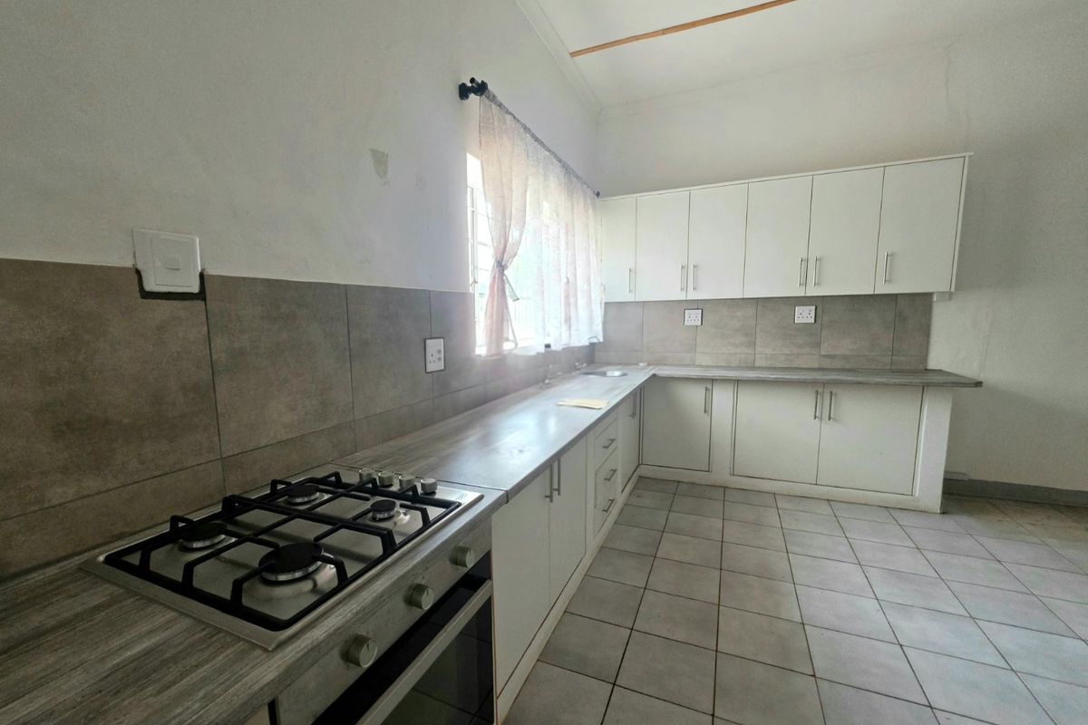 A functional kitchen featuring white cabinetry, laminate countertops, a gas hob, built-in oven, and neutral tiled flooring with a tiled backsplash.