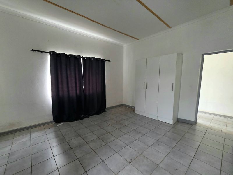 A vacant bedroom featuring tiled flooring and a built-in wardrobe, offering a clean, neutral space ready for personalization.