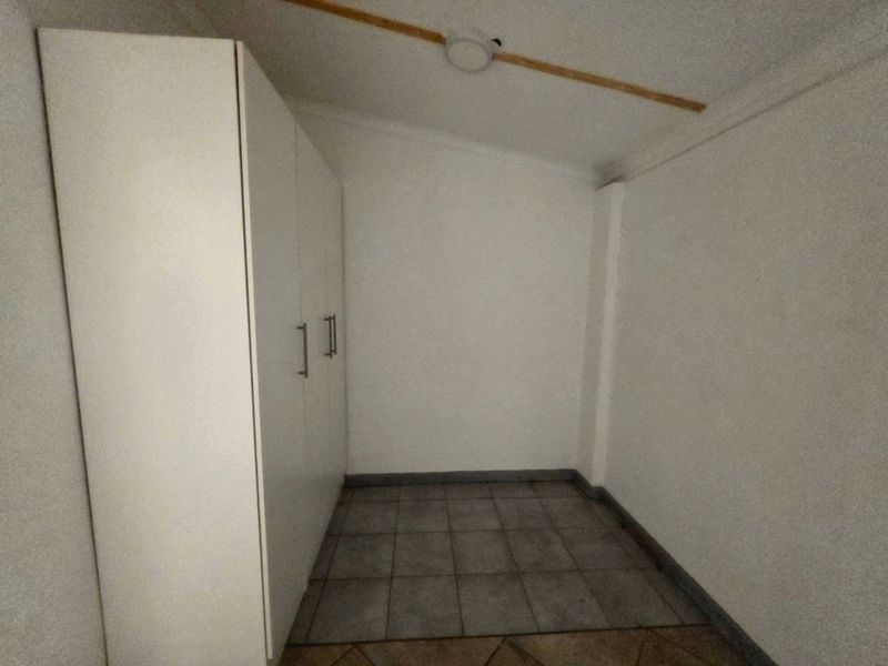 A compact, empty bedroom featuring tiled flooring and a built-in wardrobe, offering a neutral space ready for personalization.