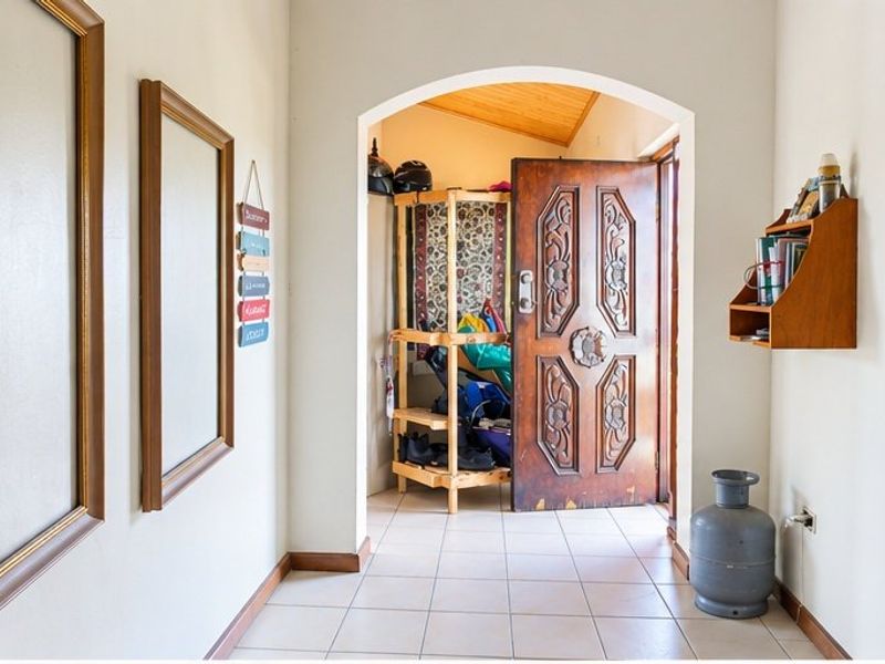 An entry hallway featuring tiled flooring and a decorative timber front door set within an arched transition space.
