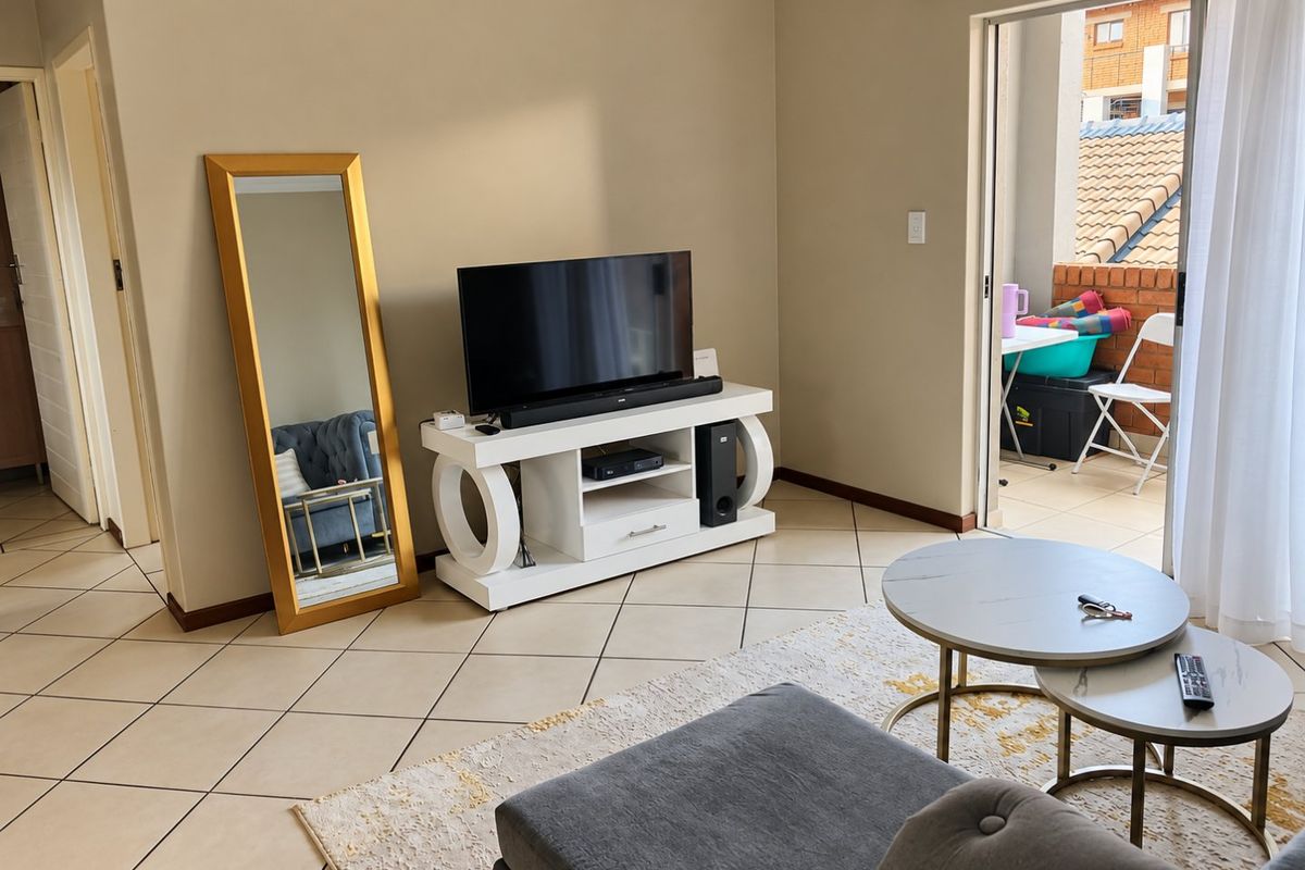 A well-maintained living room featuring tiled flooring and a sliding glass door providing access to an outdoor balcony area.
