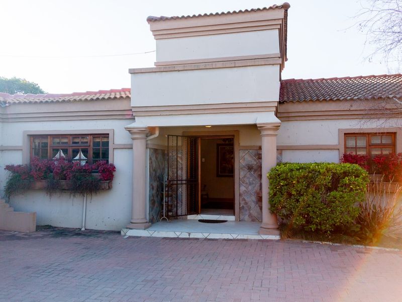 Front elevation of a single-story residence featuring a paved driveway, covered entrance porch with decorative columns, and timber-framed windows.