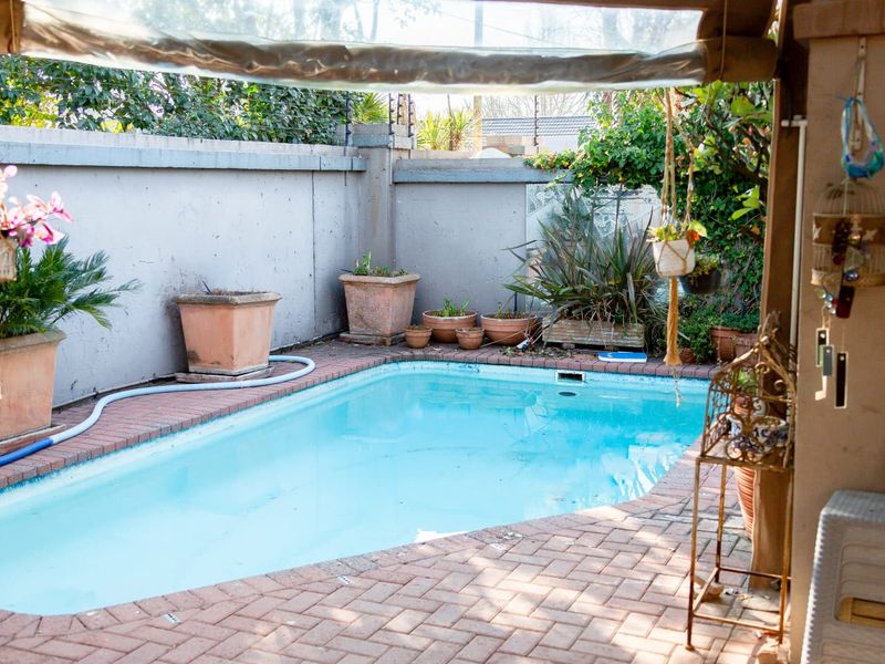 A private outdoor swimming pool area featuring brick paving and a secure perimeter wall with electric fencing.