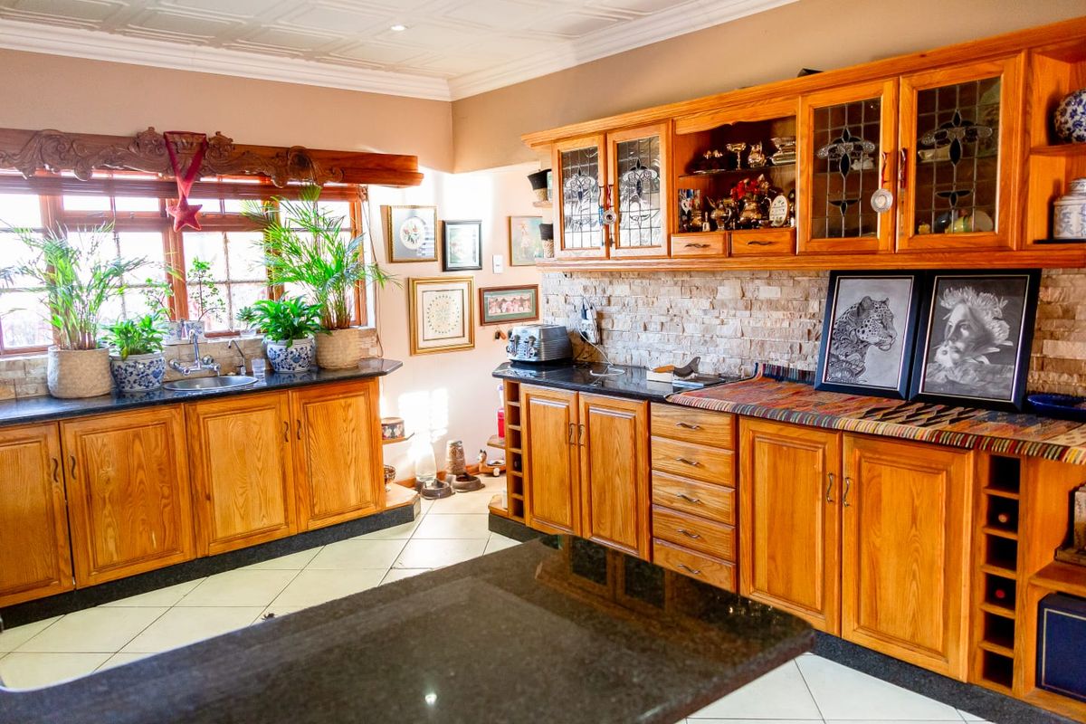 A traditional kitchen featuring extensive wooden cabinetry, granite countertops, a stone tile backsplash, and decorative ceiling detailing.