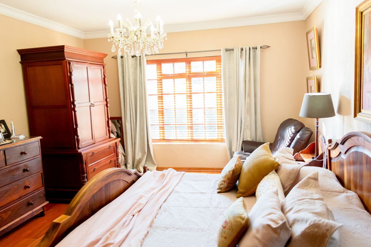 A well-maintained bedroom featuring hardwood flooring, a timber window frame, and decorative crown molding.