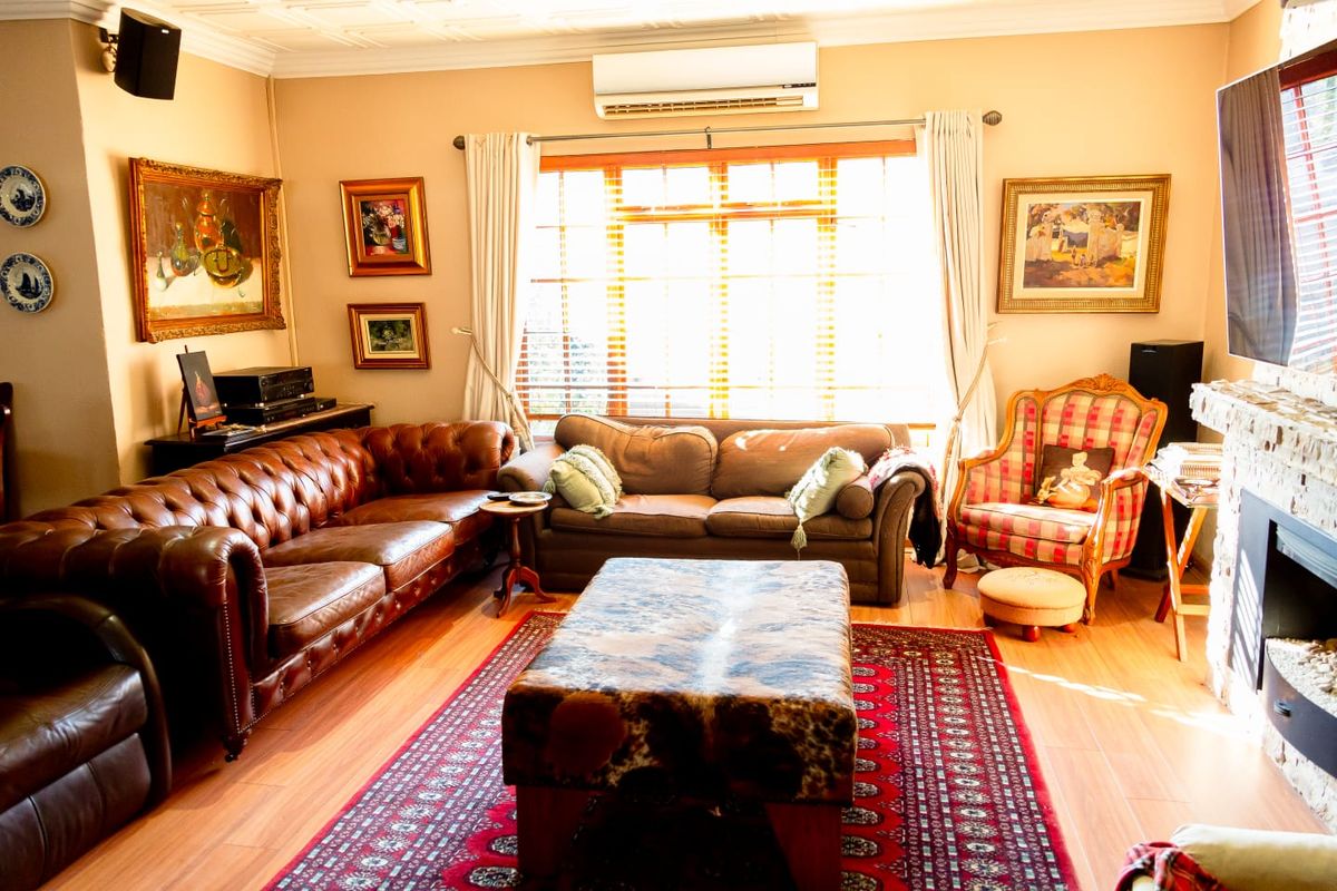 A comfortable living room featuring a fireplace, split-system air conditioning, and warm laminate flooring, creating a cozy and inviting atmosphere.