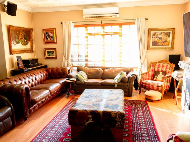 A comfortable living room featuring a fireplace, split-system air conditioning, and warm laminate flooring, creating a cozy and inviting atmosphere.