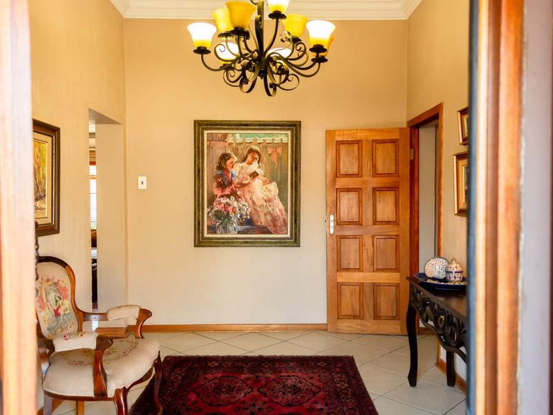 A welcoming entrance hall featuring tiled flooring, a classic wooden panel door, and a decorative wrought iron chandelier.