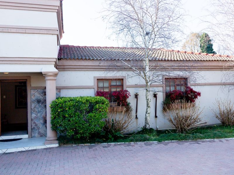 Front facade of the house featuring a paved driveway, tiled roof, decorative columns, and stone cladding accents around the entrance.
