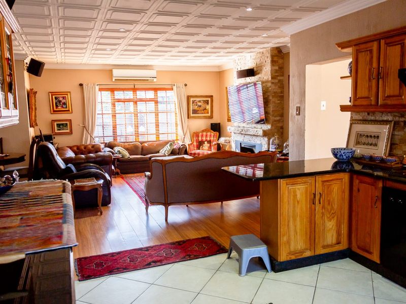 Open-plan living area featuring a stone fireplace, coffered ceiling, and a kitchen with wooden cabinetry and granite countertops.
