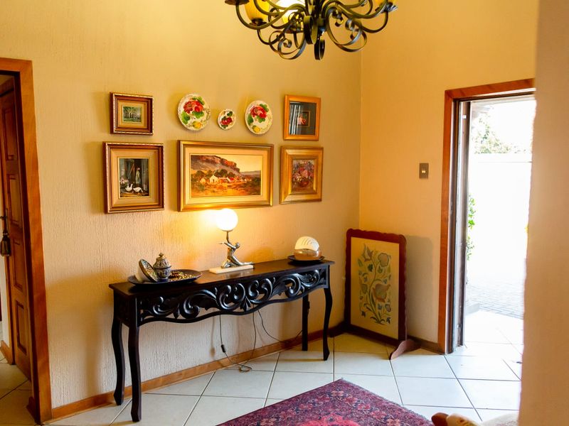 A welcoming entrance hall featuring tiled flooring, textured walls, and a decorative wrought iron chandelier, providing access to adjacent rooms.