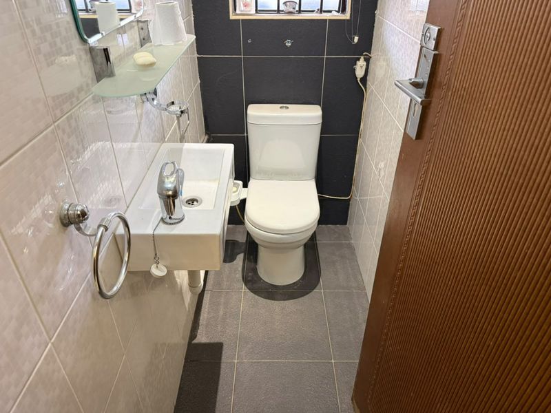 A compact guest bathroom featuring a wall-mounted basin, modern toilet, and contrasting tiled finishes.