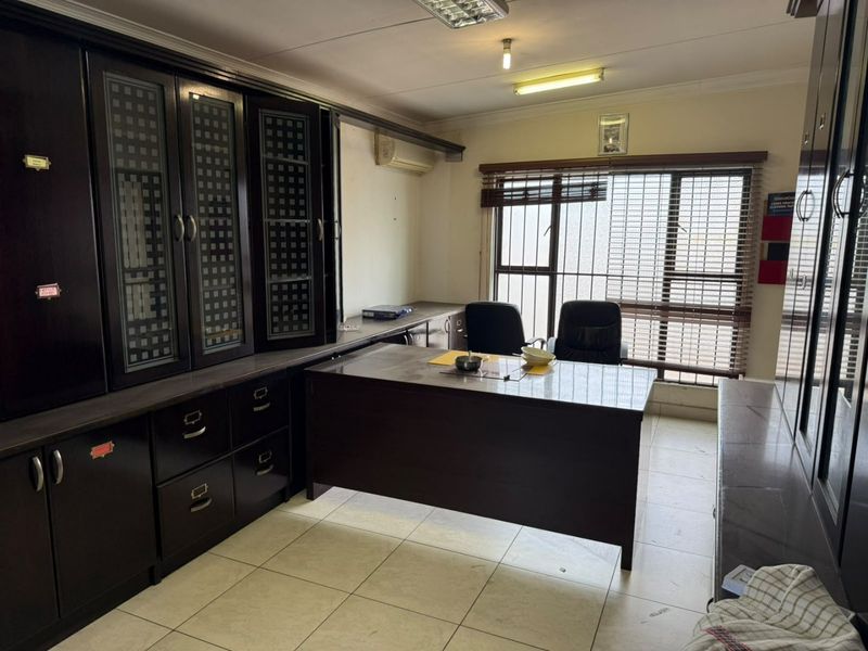 A functional home office featuring extensive built-in dark wood cabinetry, tiled flooring, and a split-system air conditioning unit.