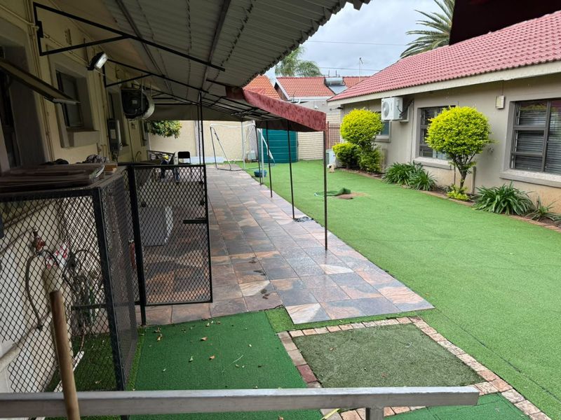 Rear exterior area featuring a covered tiled patio, artificial lawn, and secure perimeter fencing, providing a functional outdoor space.