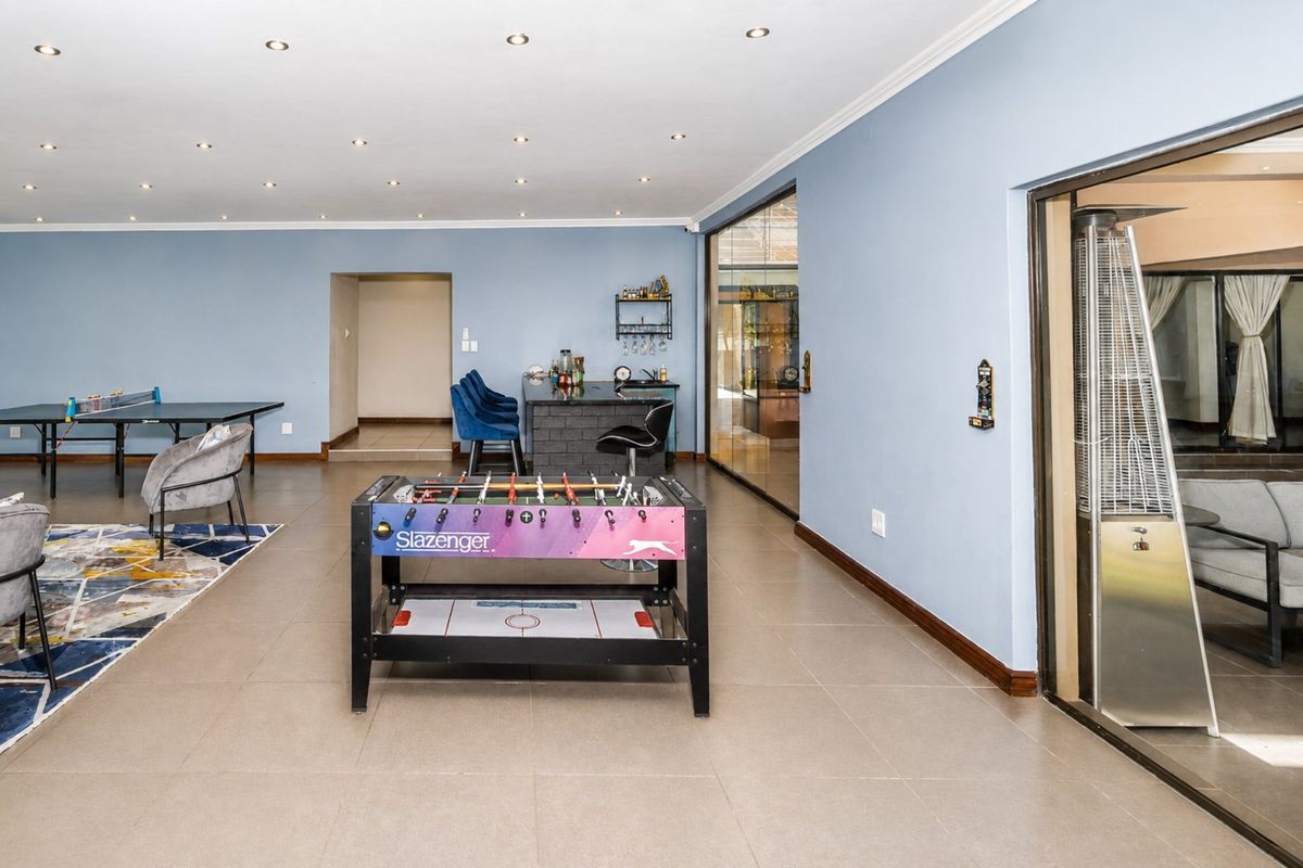 Spacious living area featuring tiled flooring, recessed lighting, and a built-in bar counter, with sliding glass doors leading to an adjacent space.