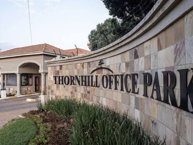 Entrance view of Thornhill Office Park featuring a stone-clad boundary wall, security gatehouse, and well-maintained landscaped surroundings.