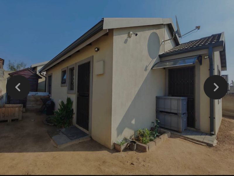 Rear exterior view of the property featuring a paved walkway, security gates, and installed satellite dish.