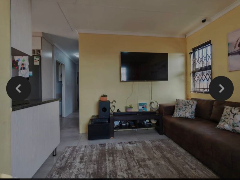 Open plan living area featuring tiled flooring, coving, and a kitchen transition, providing a functional space for daily living.