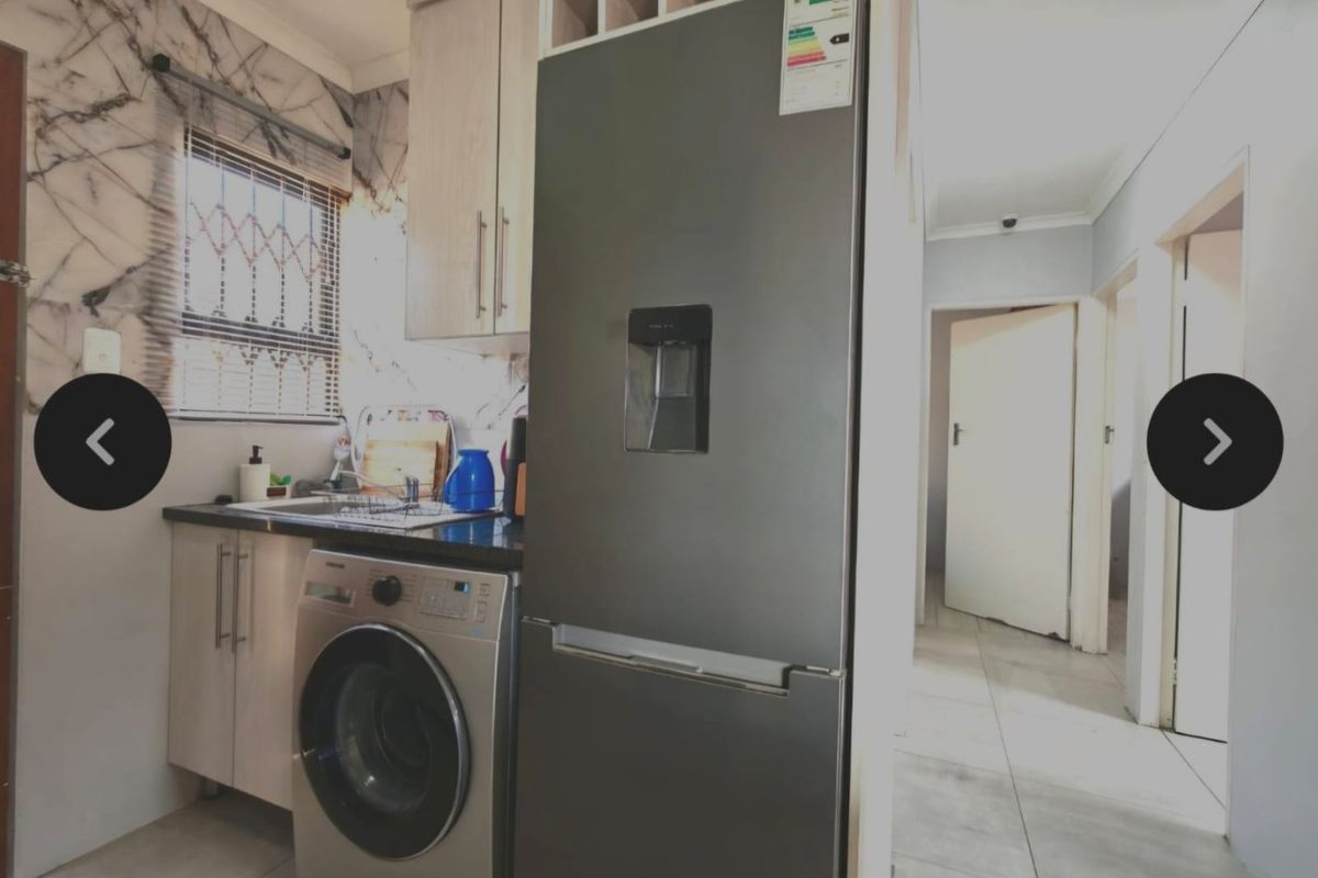 Compact kitchen featuring modern cabinetry, stone countertops, and tiled flooring, with an adjacent hallway leading to other rooms.