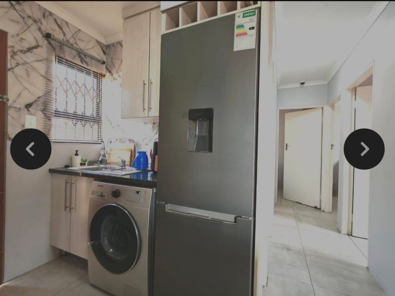 Compact kitchen featuring modern cabinetry, stone countertops, and tiled flooring, with an adjacent hallway leading to other rooms.