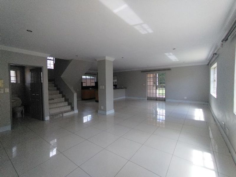 Spacious open-plan living area featuring polished tiled floors, recessed lighting, a central structural column, and direct access to the outdoor area via sliding doors.