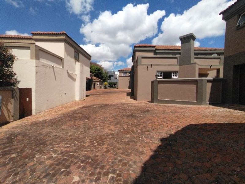 A view of the property exterior featuring a cobblestone driveway and multi-level stucco building facades with tiled roofing.