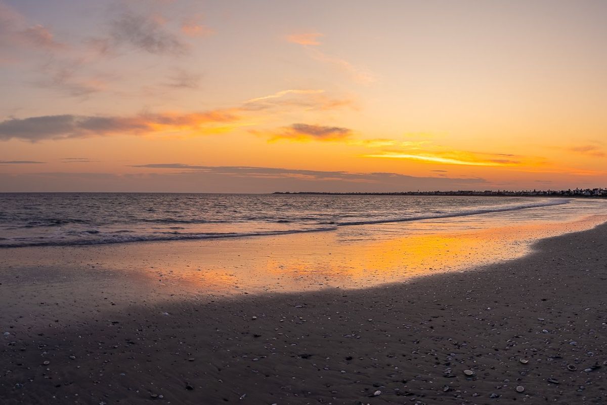 A panoramic sunset view over the ocean and sandy coastline, showcasing the natural landscape and coastal setting of the property.