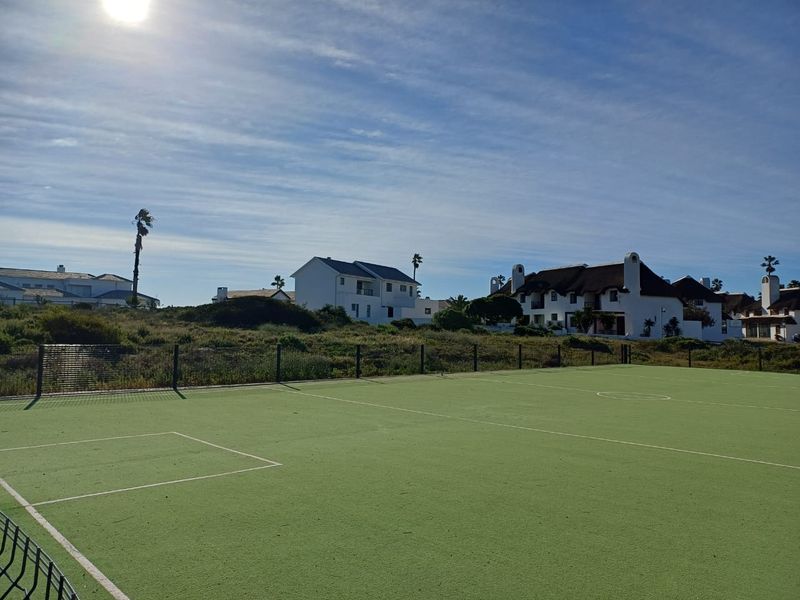 A well-maintained outdoor sports court with synthetic surfacing and perimeter fencing, situated within a residential estate setting.