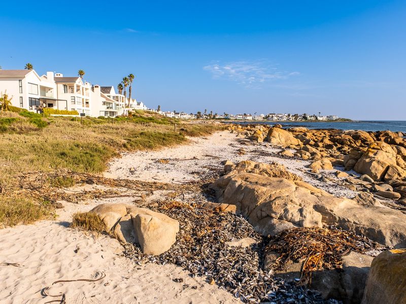 A scenic view of the rocky coastline and sandy beach adjacent to a residential coastal development.