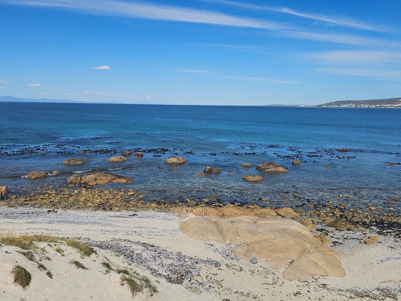 A scenic coastal view overlooking the ocean, rocky shoreline, and sandy beach area.