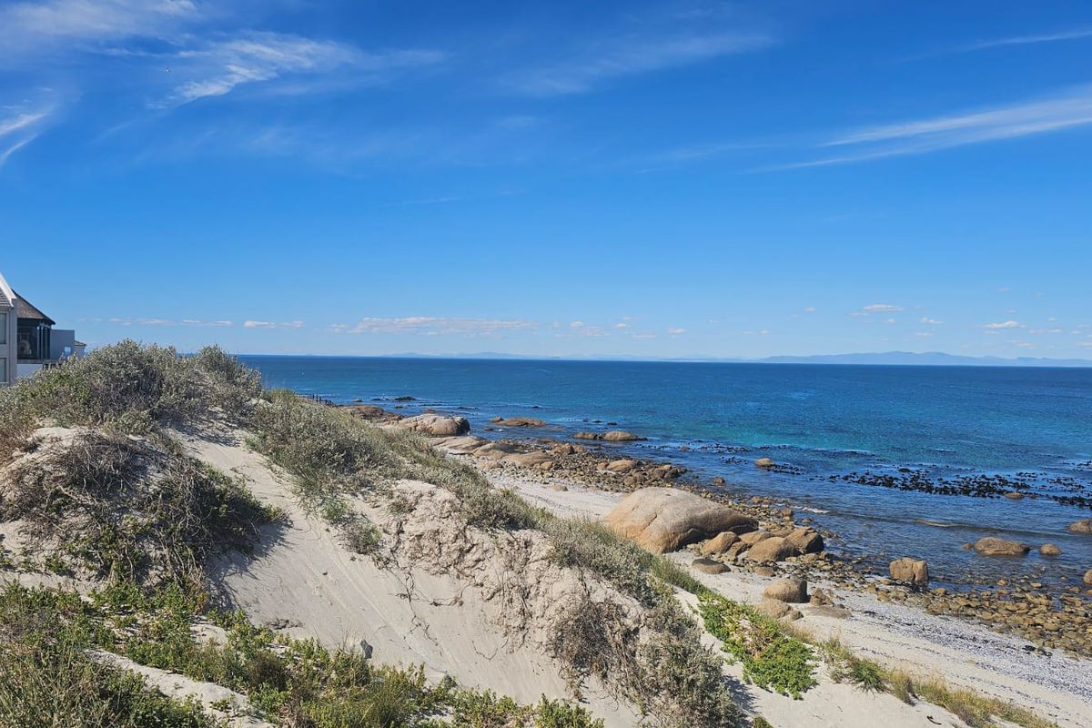 A scenic view of the coastal landscape featuring natural sand dunes, rocky shoreline, and expansive ocean vistas.