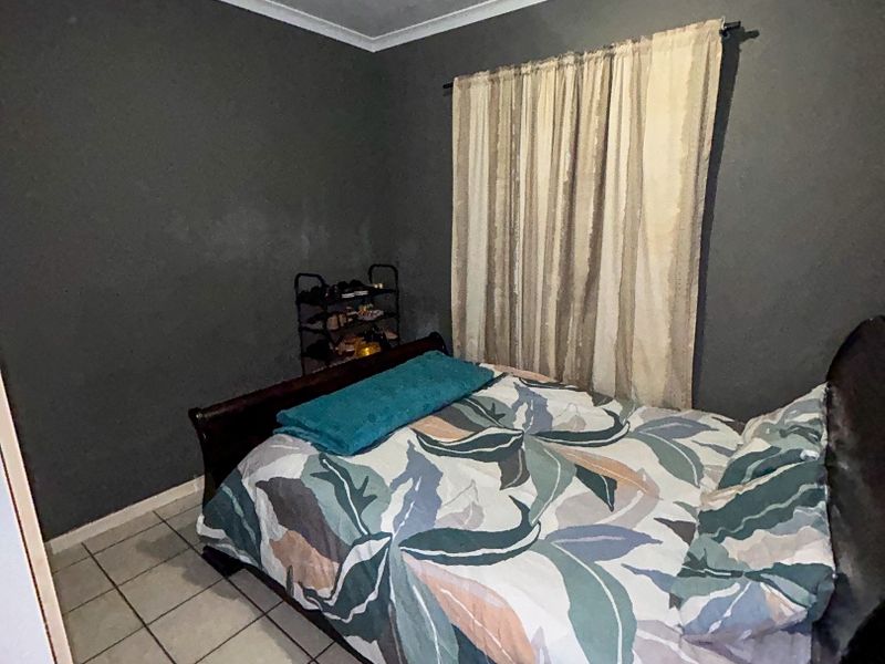 A compact bedroom featuring tiled flooring and dark grey walls, requiring minor cosmetic updates to improve the overall finish and appeal.