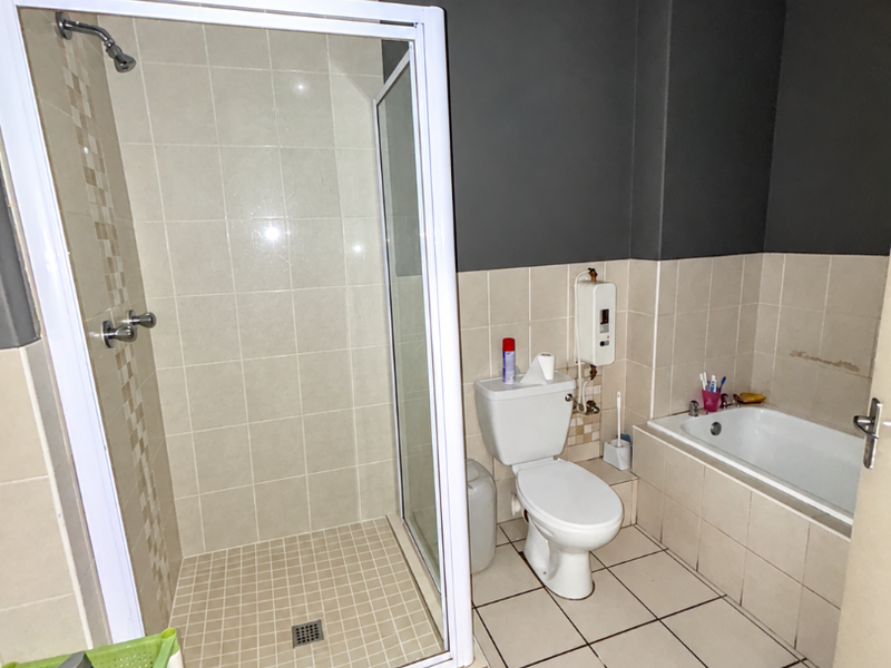 A functional bathroom featuring a separate shower enclosure, bathtub, toilet, and tiled finishes, offering a practical layout for daily use.