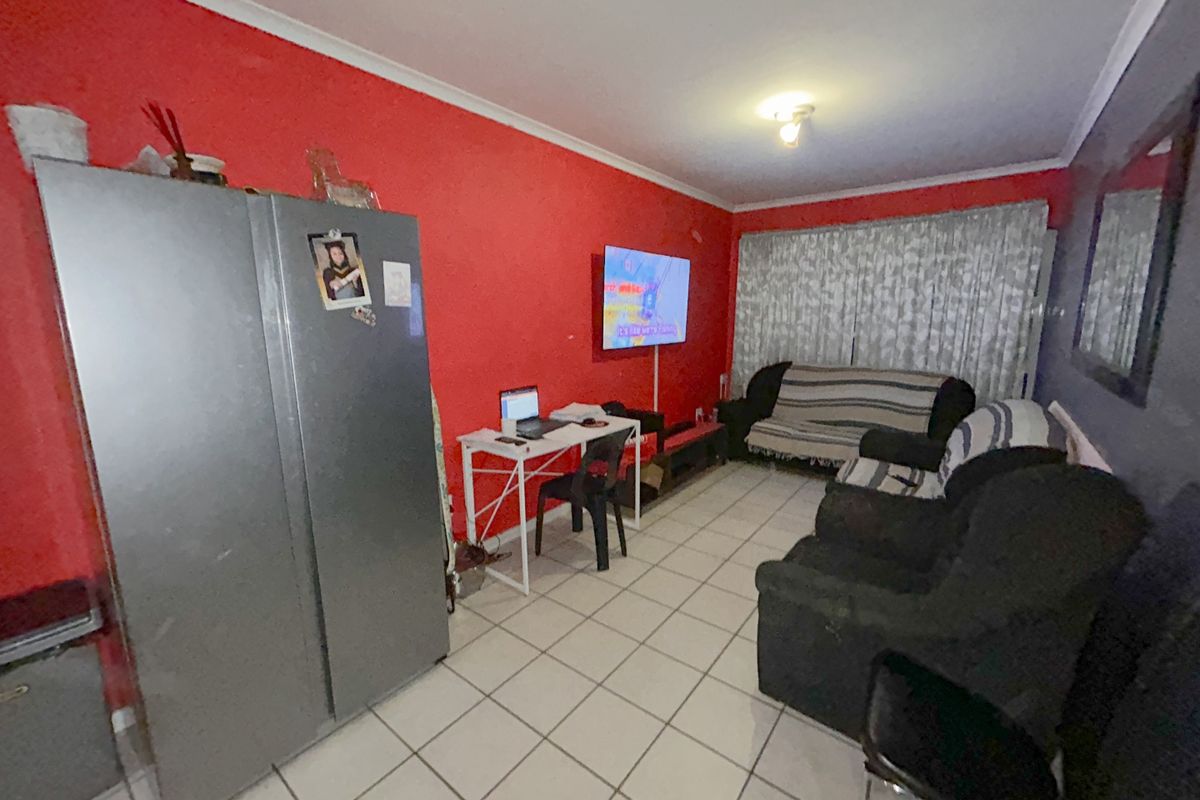 A living room featuring tiled flooring and a coved ceiling, currently utilized as a multi-purpose living and workspace area.