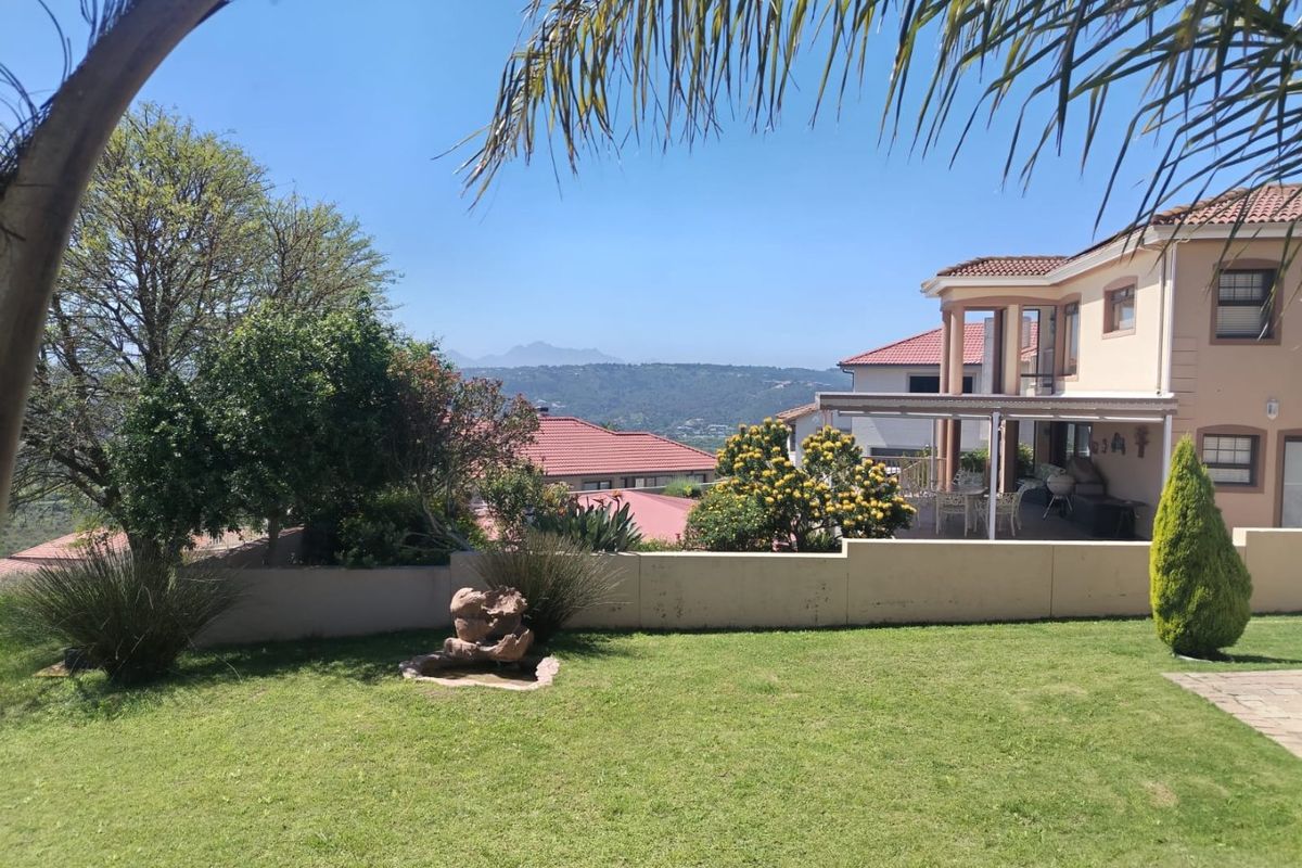 A well-maintained rear garden featuring a stone water feature, a covered patio area, and scenic mountain views.