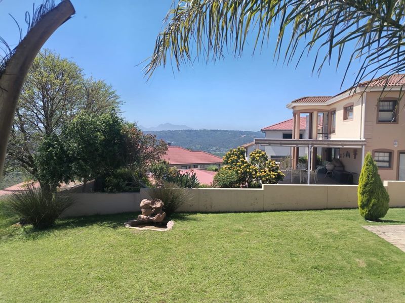 A well-maintained rear garden featuring a stone water feature, a covered patio area, and scenic mountain views.