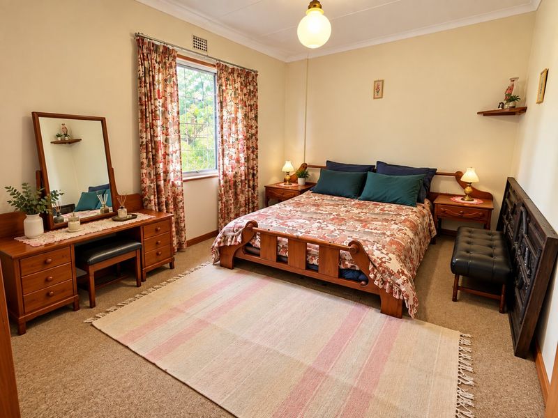 A well-maintained bedroom featuring neutral walls, carpet flooring, and a window with natural light.