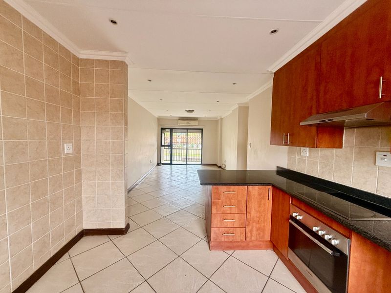 Open-plan kitchen and living area featuring tiled floors, built-in wooden cabinetry, granite countertops, and a sliding door leading to an outdoor space.