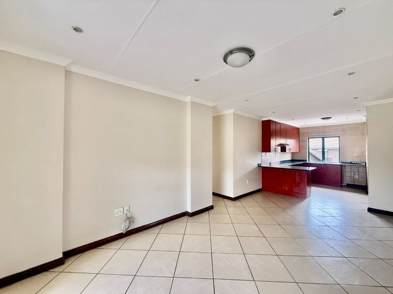 Spacious open-plan living area featuring tiled flooring, recessed lighting, and a functional kitchen with built-in cabinetry and a tiled backsplash.