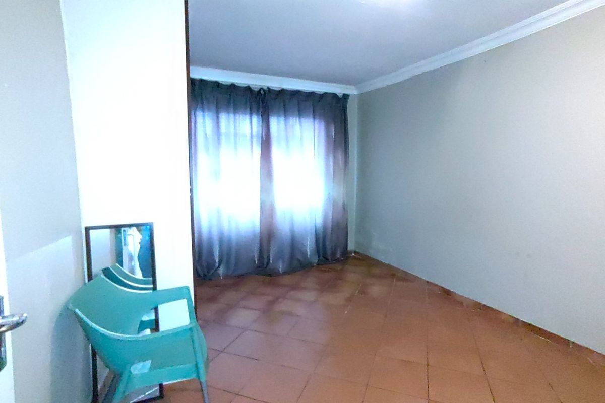 A vacant bedroom featuring tiled flooring, cove cornicing, and a window with curtain rails, offering a blank canvas for renovation.