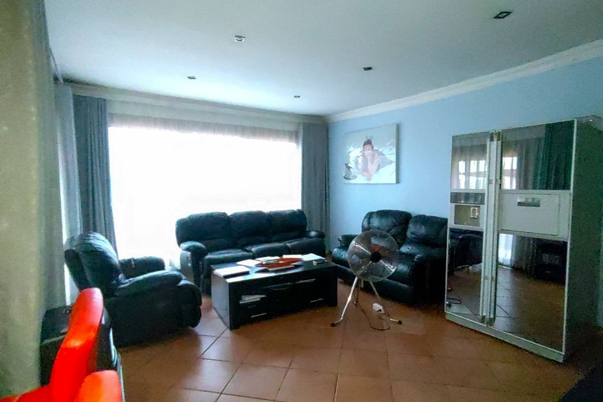 A living room featuring tiled flooring, recessed downlighting, and a large window allowing natural light into the space.
