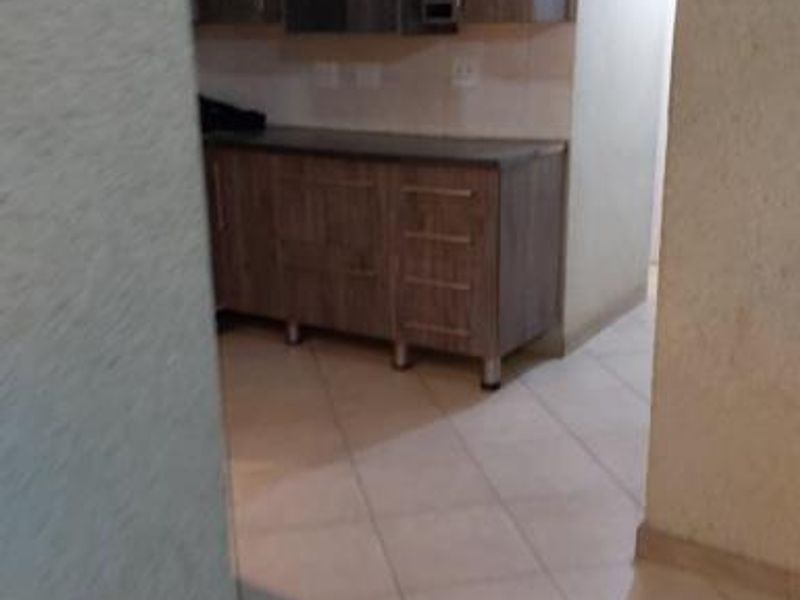 A functional scullery or secondary kitchen area featuring built-in wood-look cabinetry, integrated wine storage, and tiled flooring.