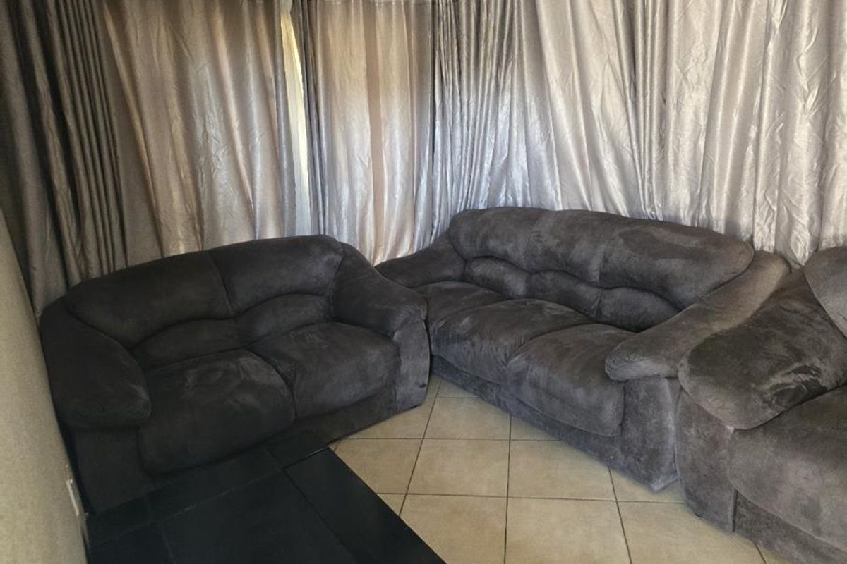 A living room area featuring tiled flooring and full-length window curtains.