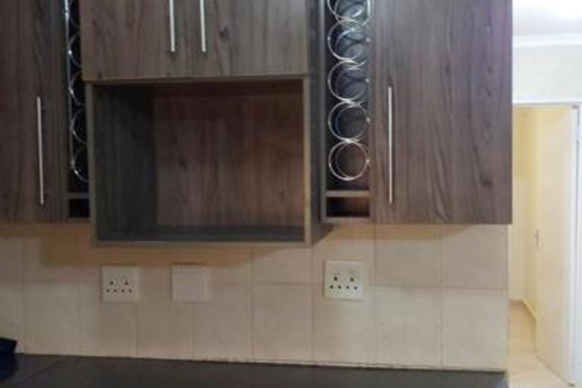 A functional kitchen area featuring dark wood-grain cabinetry, integrated wine storage, and a tiled backsplash with a dark countertop.