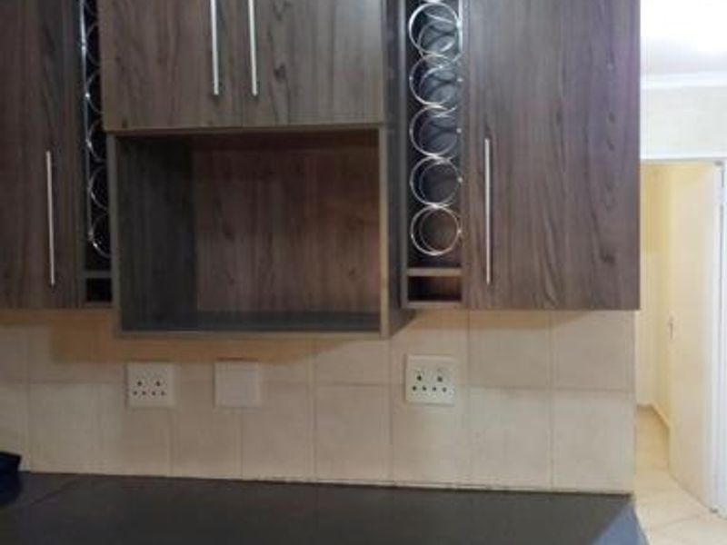 A functional kitchen area featuring dark wood-grain cabinetry, integrated wine storage, and a tiled backsplash with a dark countertop.