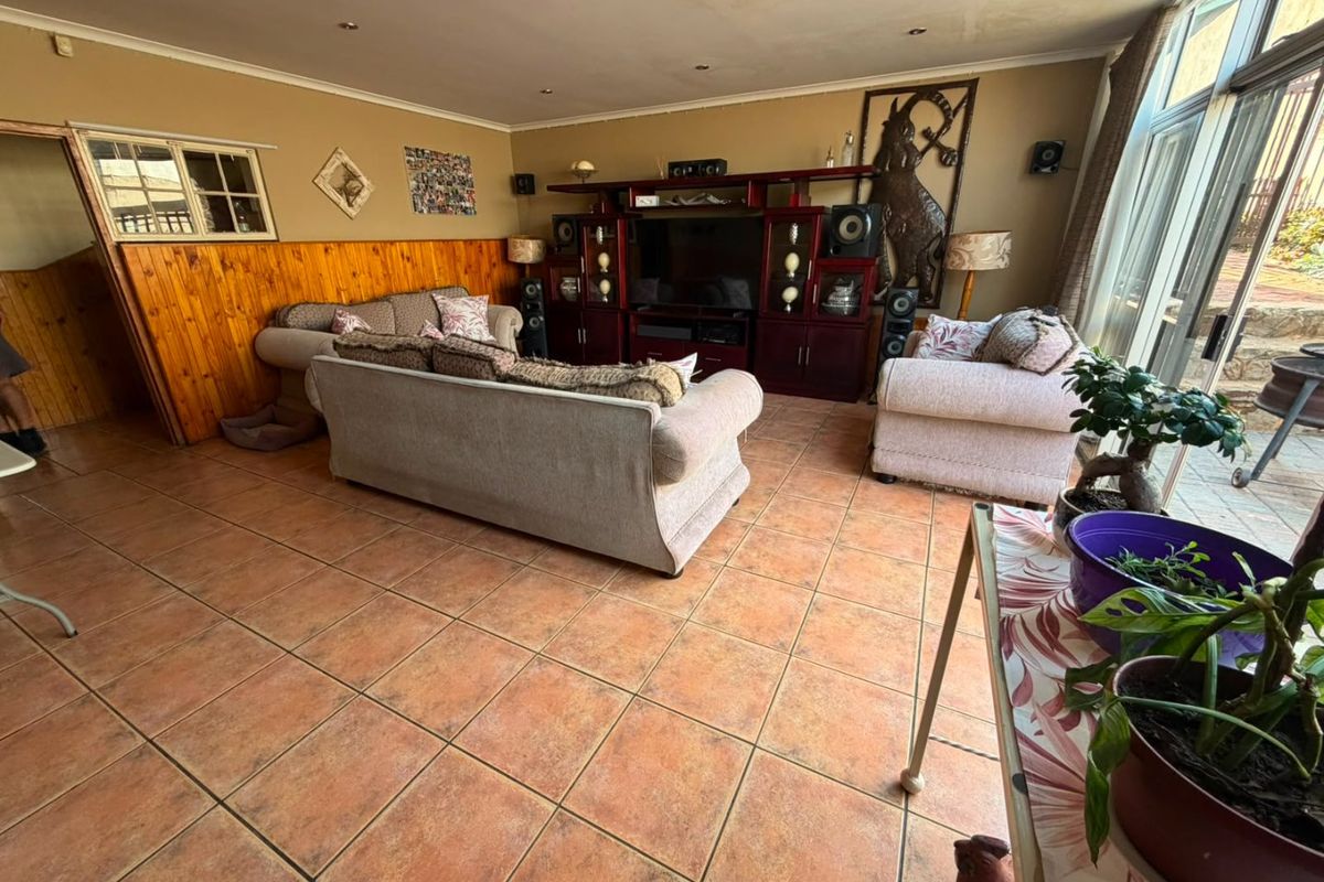 Spacious living room featuring tiled flooring, timber wall paneling, and large sliding glass doors providing access to the outdoor area.