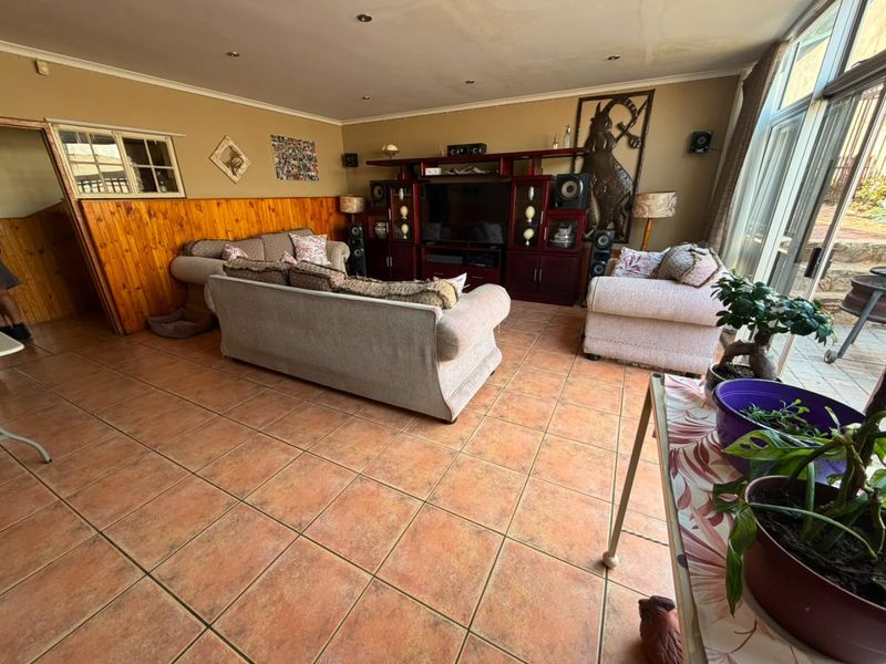 Spacious living room featuring tiled flooring, timber wall paneling, and large sliding glass doors providing access to the outdoor area.