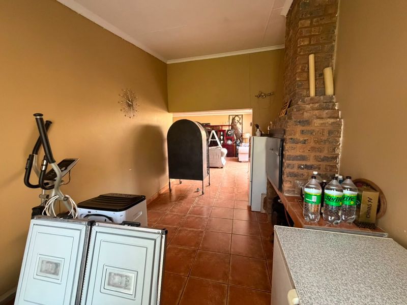 Living area featuring an exposed brick fireplace and tiled flooring, providing a functional space with potential for modernization.